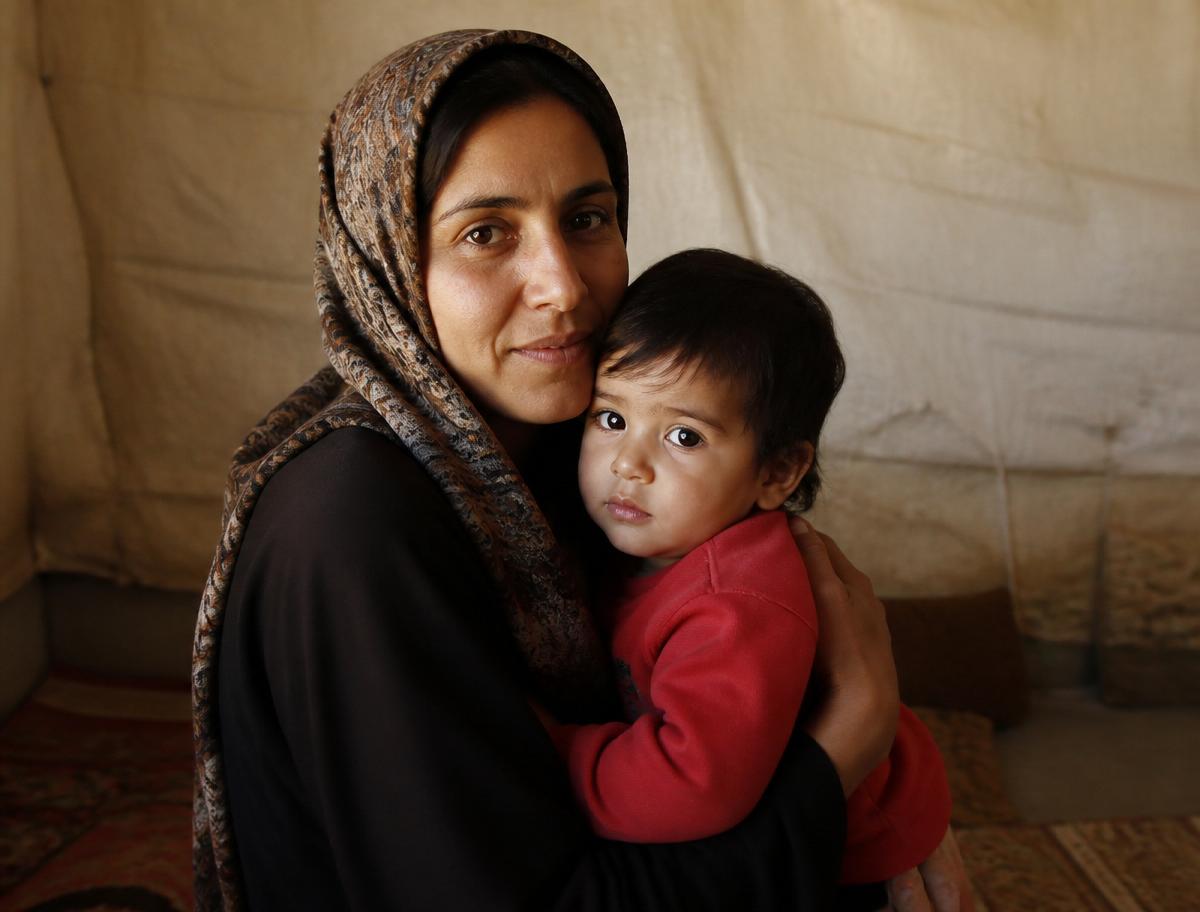 A mother holds her small child close inside a temporary shelter.